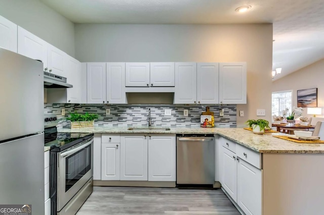 2139 Hickory Bnd SE Unit E, Conyers, GA 30013 - kitchen featuring stainless steel appliances, a peninsula, white cabinets, light wood-style flooring, and lofted ceiling