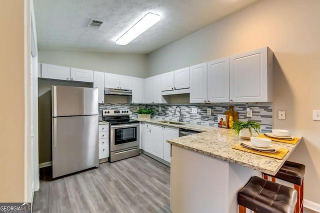 2139 Hickory Bnd SE Unit E, Conyers, GA 30013 - kitchen featuring appliances with stainless steel finishes, lofted ceiling, a peninsula, decorative backsplash, and under cabinet range hood