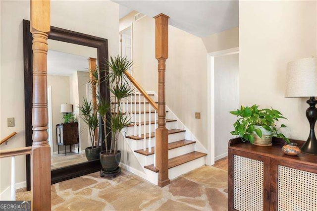 stairway with ornate columns, visible vents, and baseboards