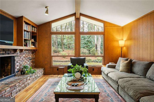 living room with lofted ceiling with beams, wooden walls, a fireplace, and wood finished floors