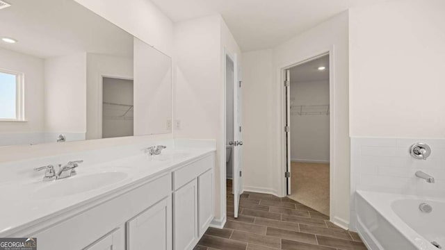 1069 Blue Juniper Cir, Loganville, GA 30052 - full bathroom with a garden tub, a sink, a walk in closet, and wood tiled floor