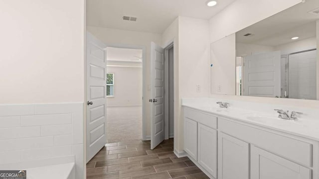 1069 Blue Juniper Cir, Loganville, GA 30052 - bathroom with double vanity, visible vents, a sink, and wood finish floors