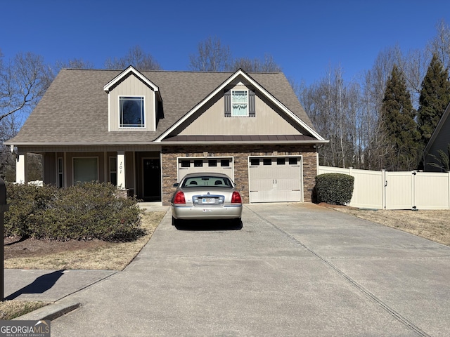 view of front of property featuring roof with shingles, concrete driveway, a gate, fence, and a garage