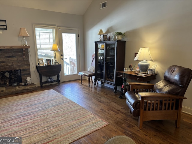 sitting room with lofted ceiling, a fireplace, wood finished floors, visible vents, and baseboards