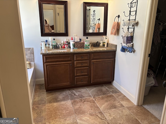 bathroom with a sink, baseboards, and double vanity