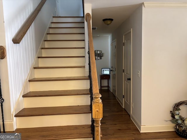 stairway featuring visible vents, baseboards, and wood finished floors