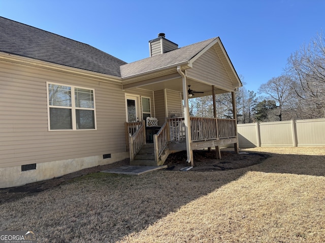 rear view of property featuring a shingled roof, ceiling fan, a chimney, crawl space, and fence