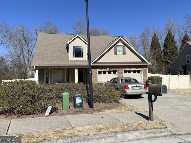 view of front facade with driveway, a garage, a standing seam roof, a gate, and fence