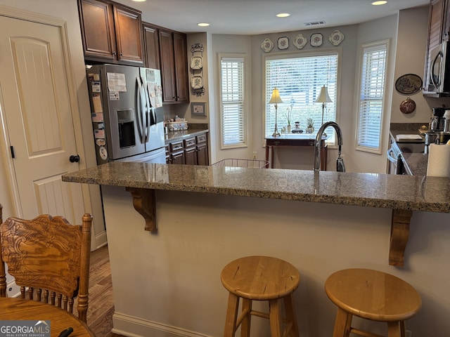 kitchen with dark stone countertops, visible vents, stainless steel appliances, and a wealth of natural light