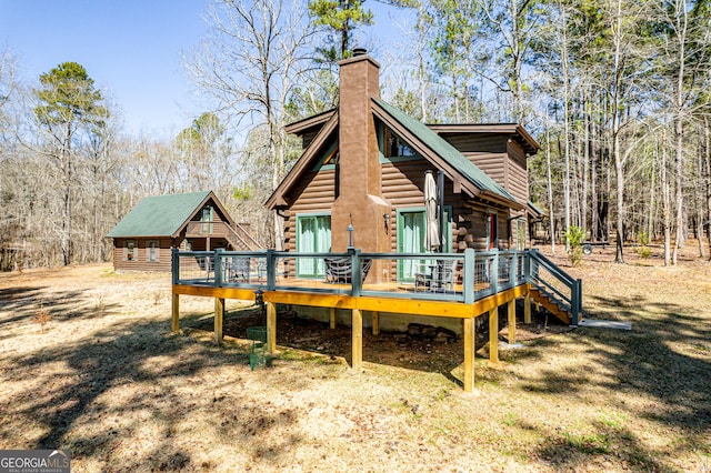 rear view of house featuring a chimney, log exterior, and a wooden deck