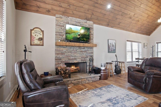 living area featuring lofted ceiling, wooden ceiling, a fireplace, and wood finished floors