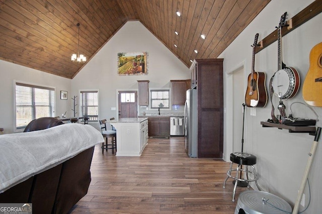 kitchen featuring wooden ceiling, stainless steel appliances, wood finished floors, open floor plan, and a kitchen bar