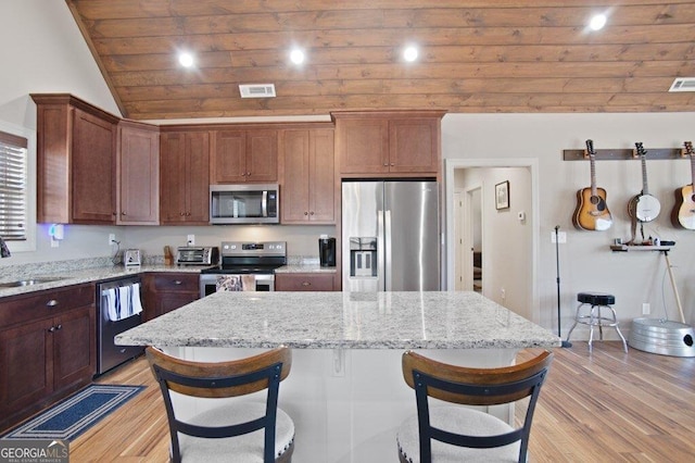 kitchen featuring appliances with stainless steel finishes, light wood-style flooring, and a breakfast bar area