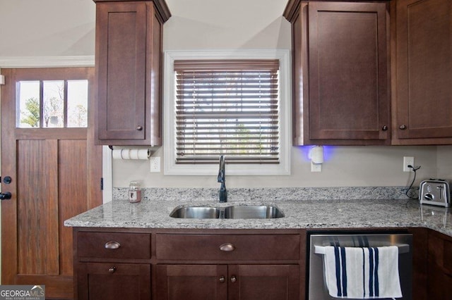 kitchen with light stone countertops, dishwashing machine, and a sink