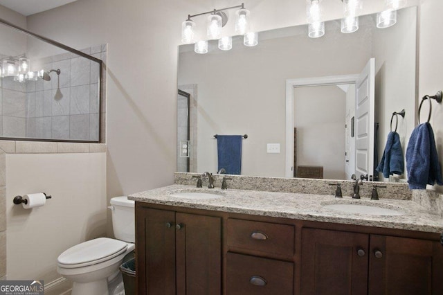 full bath featuring double vanity, tiled shower, a sink, and toilet