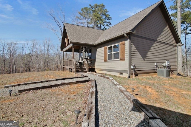 view of side of home with a shingled roof, crawl space, and central AC