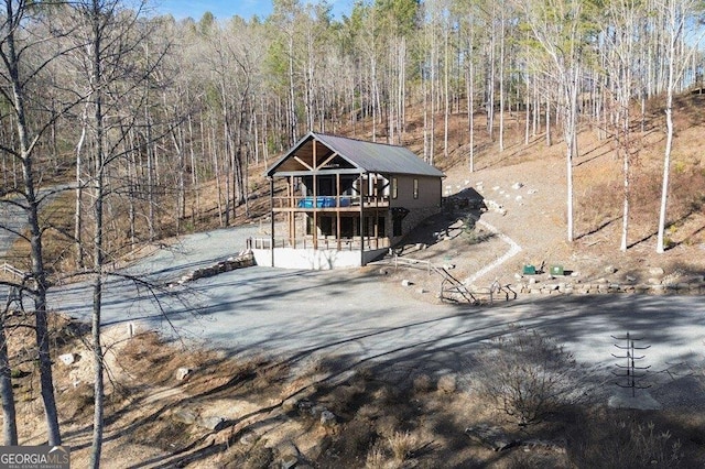 rustic home with a deck, aphalt driveway, and a wooded view