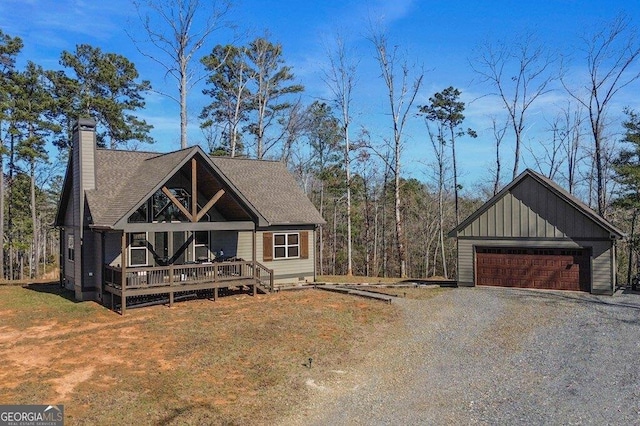 view of front facade with roof with shingles, a chimney, a front yard, a deck, and a garage