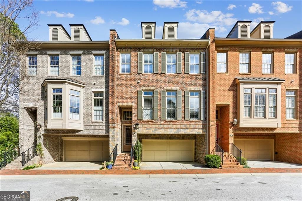 multi unit property featuring an attached garage and brick siding