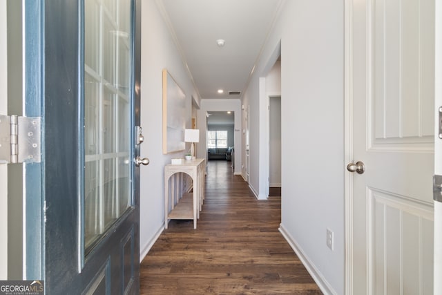 hallway featuring dark wood-type flooring, crown molding, and baseboards