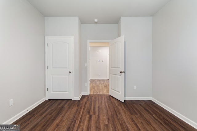 unfurnished bedroom with dark wood-style flooring and baseboards