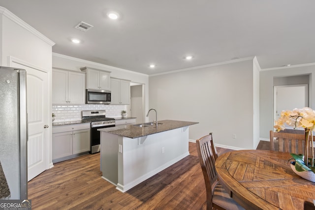 kitchen featuring stainless steel appliances, visible vents, backsplash, dark wood-type flooring, and a sink