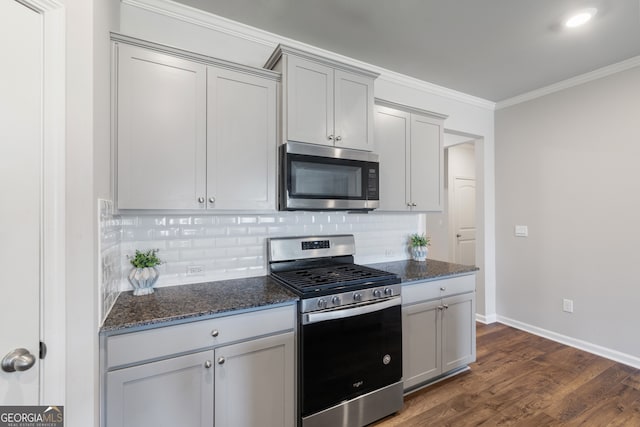 kitchen with ornamental molding, stainless steel appliances, tasteful backsplash, and dark stone countertops