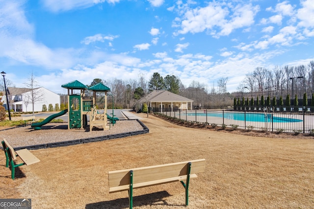 communal playground featuring a community pool and fence