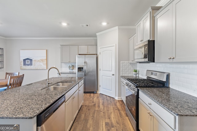 kitchen featuring stainless steel appliances, visible vents, ornamental molding, a sink, and wood finished floors