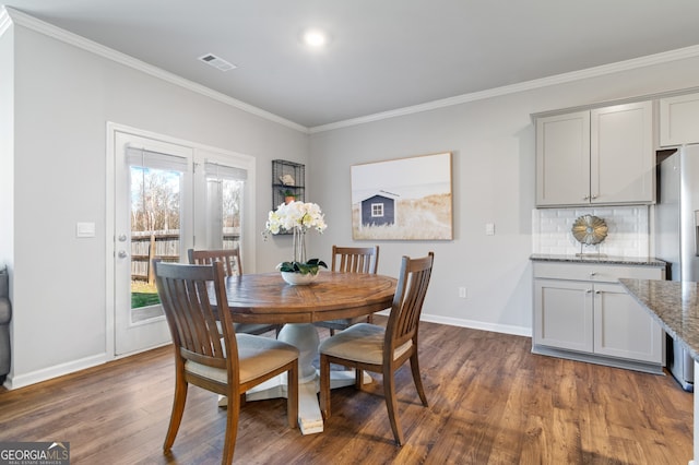 dining area with baseboards, visible vents, dark wood-type flooring, and crown molding