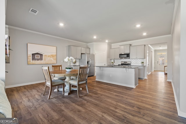 dining space with ornamental molding, dark wood-style flooring, visible vents, and baseboards