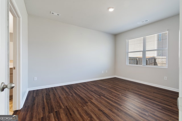 empty room featuring baseboards, visible vents, and dark wood-style flooring