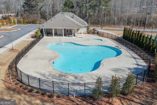 pool featuring fence, a hot tub, an outdoor structure, and a patio