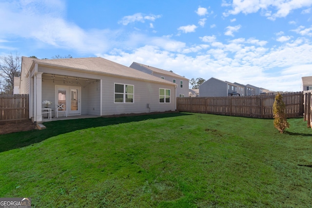 rear view of property featuring a patio, a lawn, and a fenced backyard