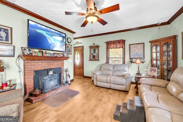 living room with a ceiling fan, a wood stove, crown molding, and light wood-style flooring