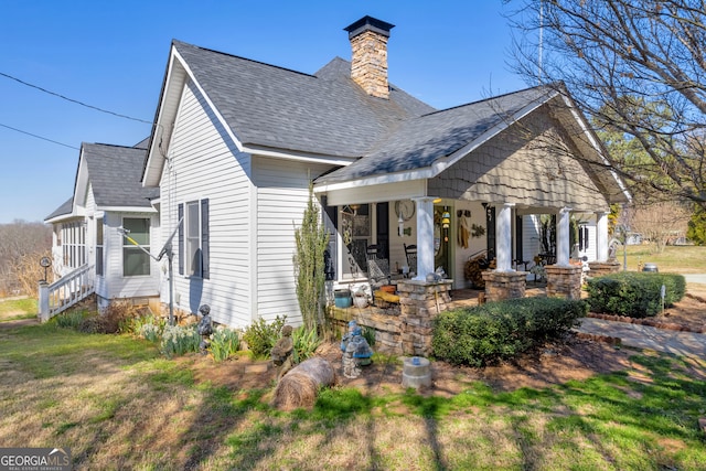 view of front of house with a shingled roof, a chimney, and a front yard