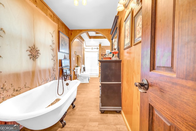 bathroom featuring a freestanding bath, wood walls, and wood finished floors