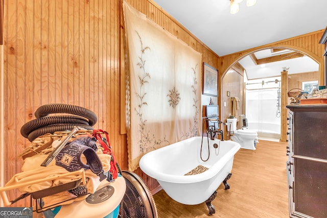 full bathroom featuring a soaking tub, wooden walls, ornamental molding, and wood finished floors