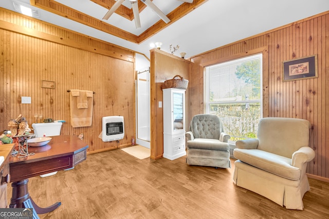 sitting room with ceiling fan, wooden walls, wood finished floors, and heating unit