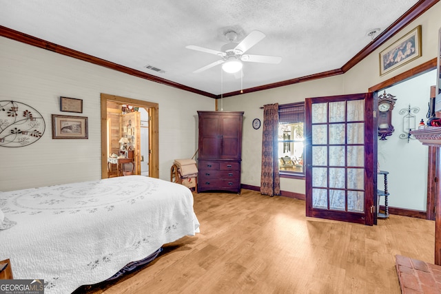 bedroom featuring ornamental molding, light wood-type flooring, visible vents, and a textured ceiling