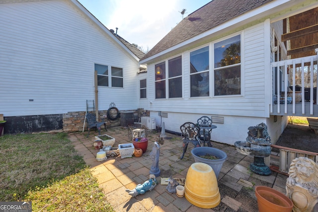 rear view of house with a shingled roof, crawl space, a patio, and central air condition unit