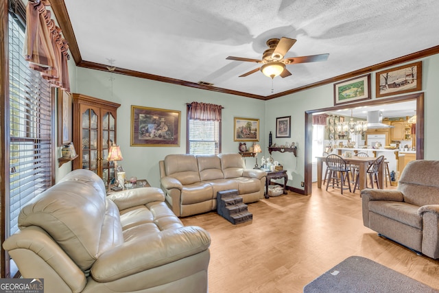 living room with wood finished floors, visible vents, baseboards, a ceiling fan, and crown molding