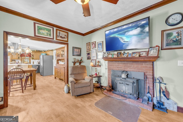 living room featuring ornamental molding, a wood stove, a textured ceiling, light wood-style floors, and ceiling fan with notable chandelier