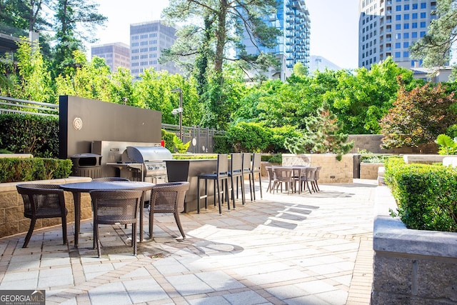 3445 Stratford Rd NE Unit 1605, Atlanta, GA 30326 - view of patio featuring outdoor dining area, fence, exterior kitchen, a city view, and area for grilling