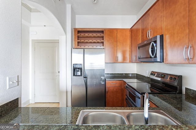 3445 Stratford Rd NE Unit 1605, Atlanta, GA 30326 - kitchen with stainless steel appliances, arched walkways, a sink, dark countertops, and brown cabinetry
