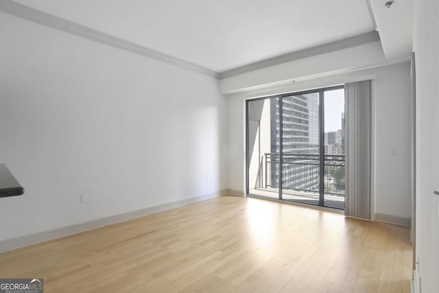 spare room featuring baseboards, crown molding, and wood finished floors