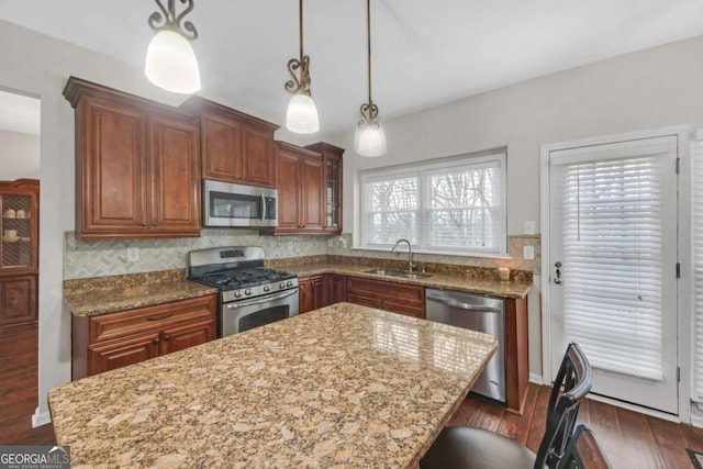 kitchen with dark wood-style flooring, stainless steel appliances, decorative backsplash, a sink, and light stone countertops