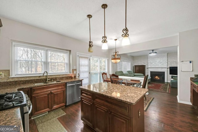 kitchen with appliances with stainless steel finishes, a sink, a lit fireplace, and dark wood-style floors