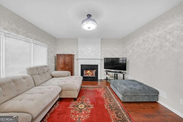 living area with a large fireplace, baseboards, and wood finished floors