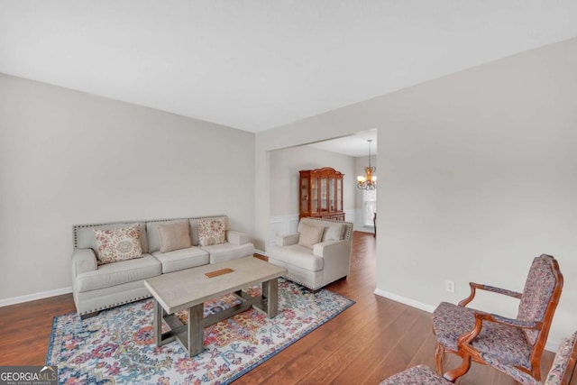 living room featuring a chandelier, baseboards, and wood finished floors